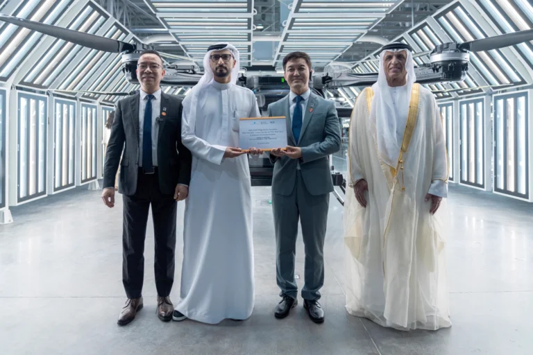 Four men standing in front of the flying car, two of them holding a framed certificate