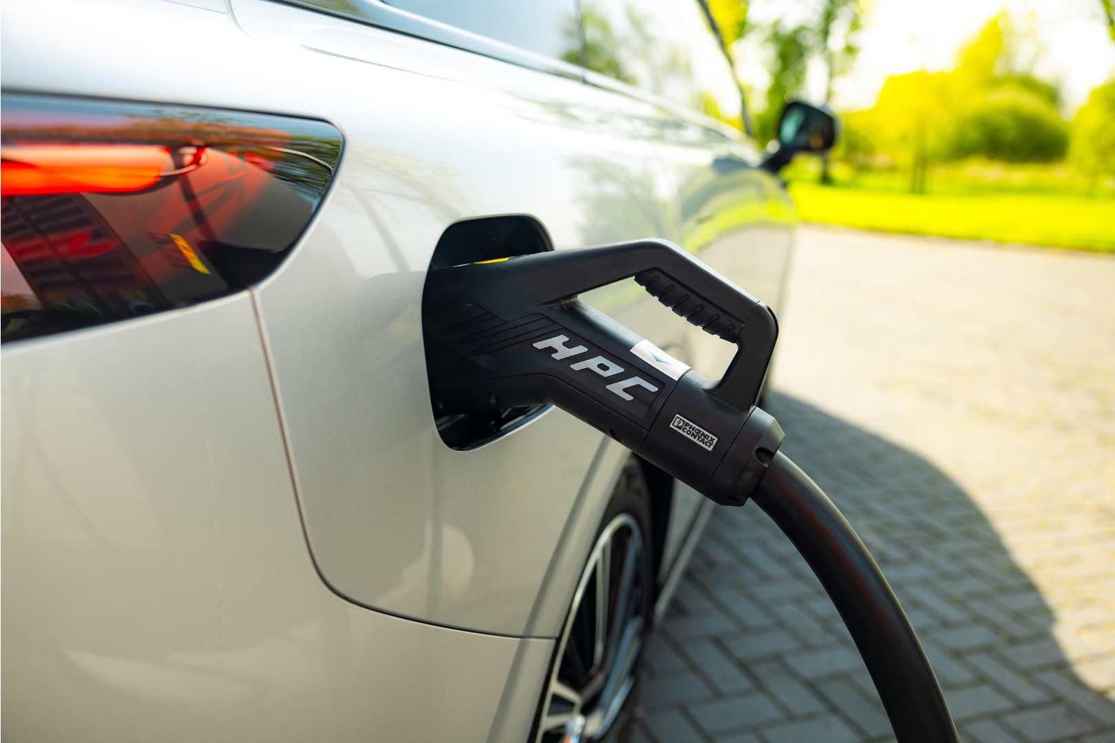 A DC charging connector marked HPC plugged into the rear charge port of a silver XPENG