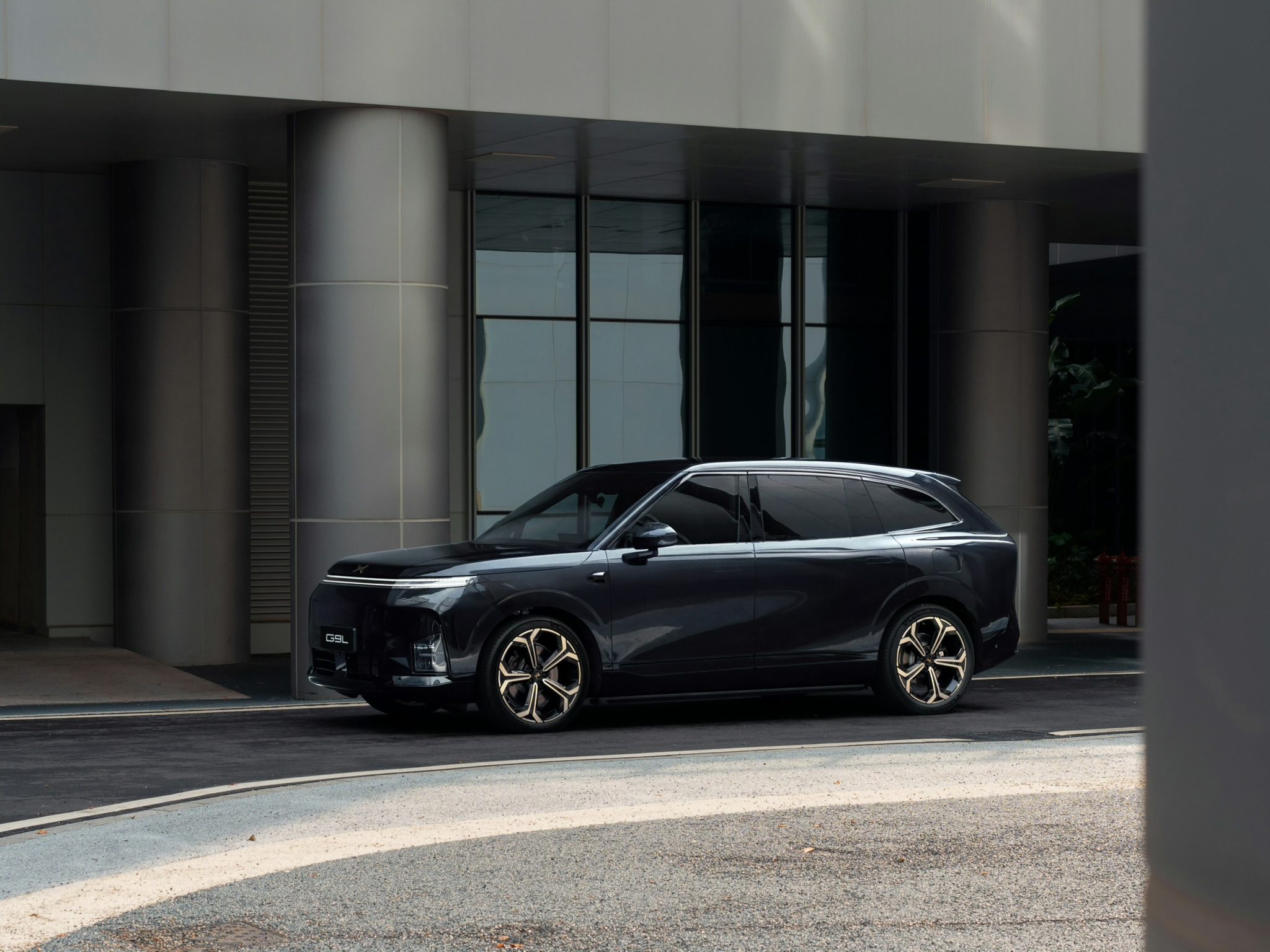 XPENG G9L Black Gold Edition seen from the side in front of a grey building