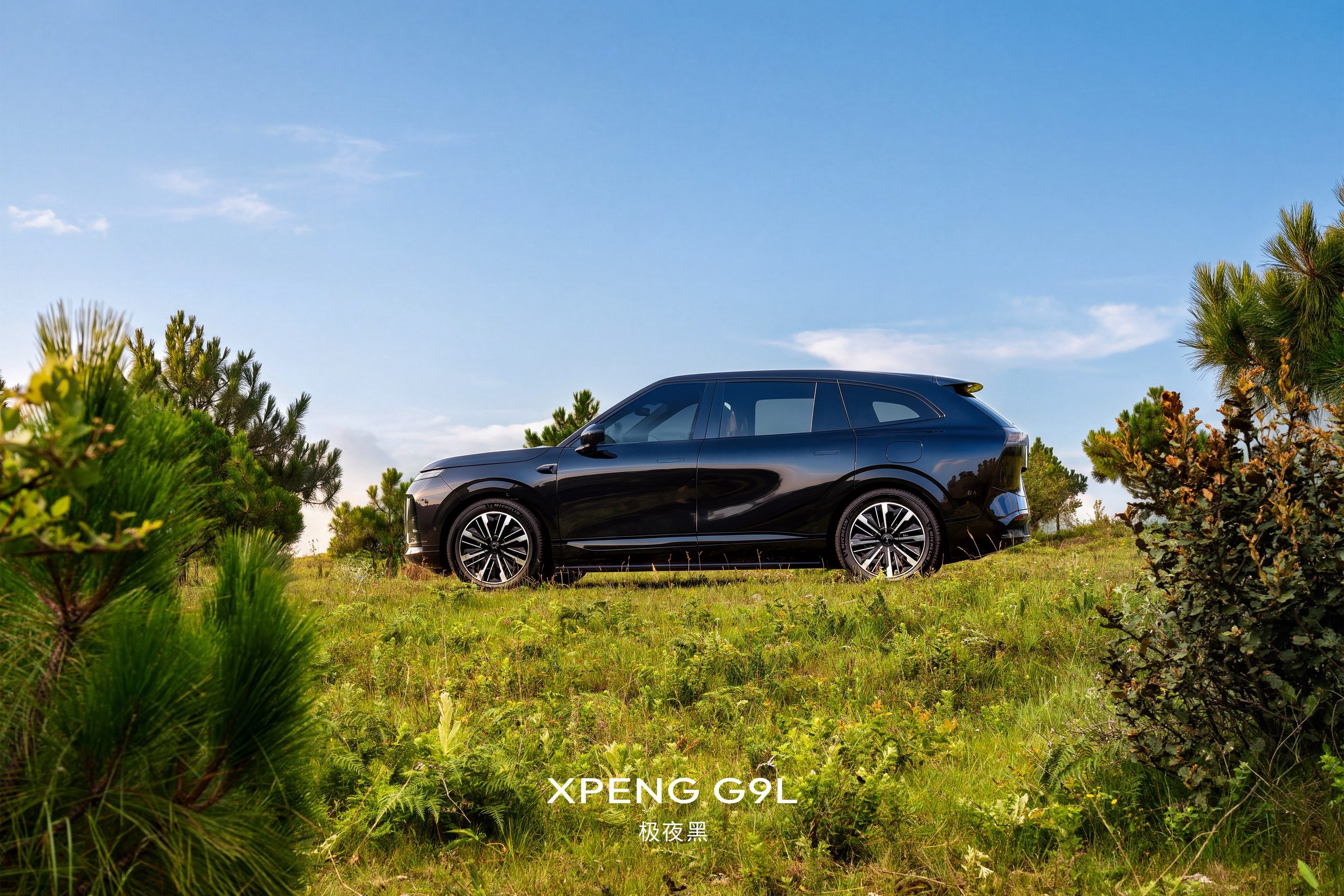 XPENG G9L in Polar Night Black, full side profile between pine trees under a blue sky