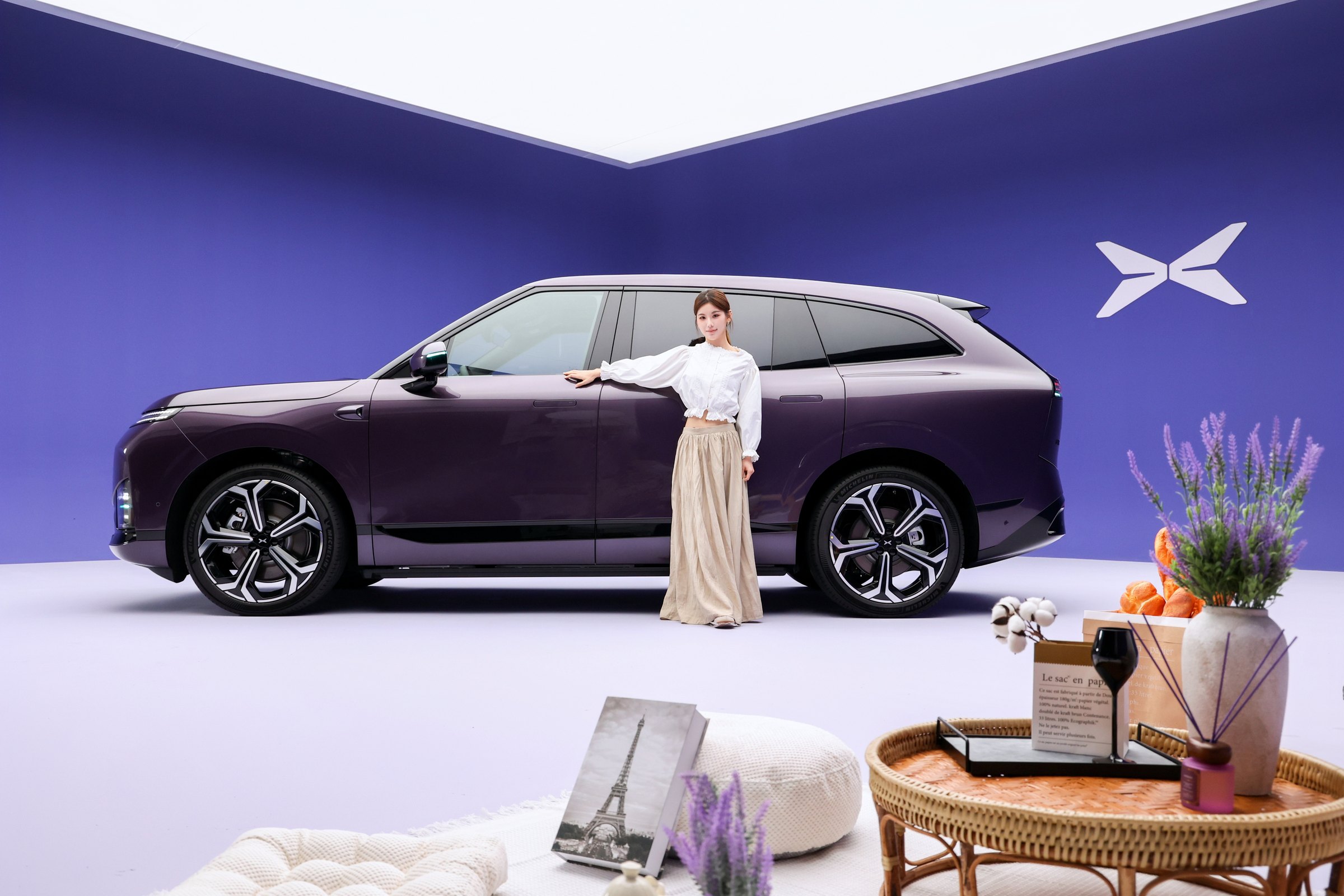 XPENG G9L i Provence Purple sideprofil i et lilla studie med lifestyle-rekvisitter