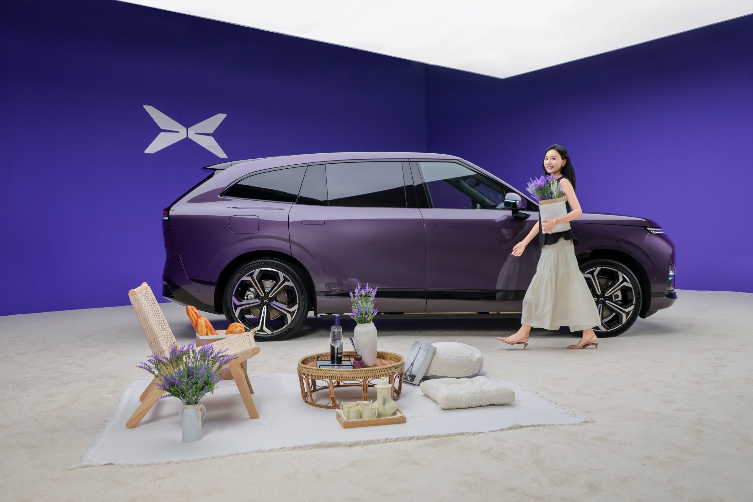 XPENG G9L i Provence Purple sideprofil i et lilla studie med en kvinde, der bærer lavendel