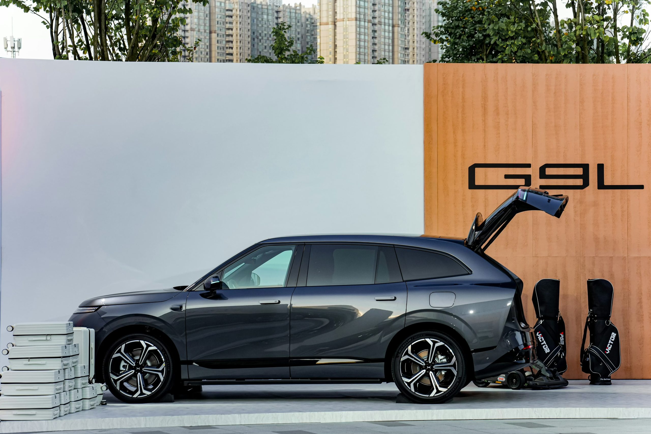 XPENG G9L in dark grey, side profile with the tailgate open, on the Guangzhou launch display stand