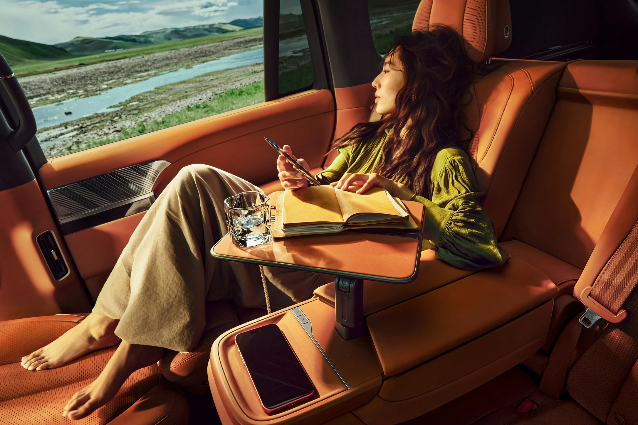 XPENG G9L Sahara Orange bagsæde i lounge-stilling med administrativ midterkonsol og bord
