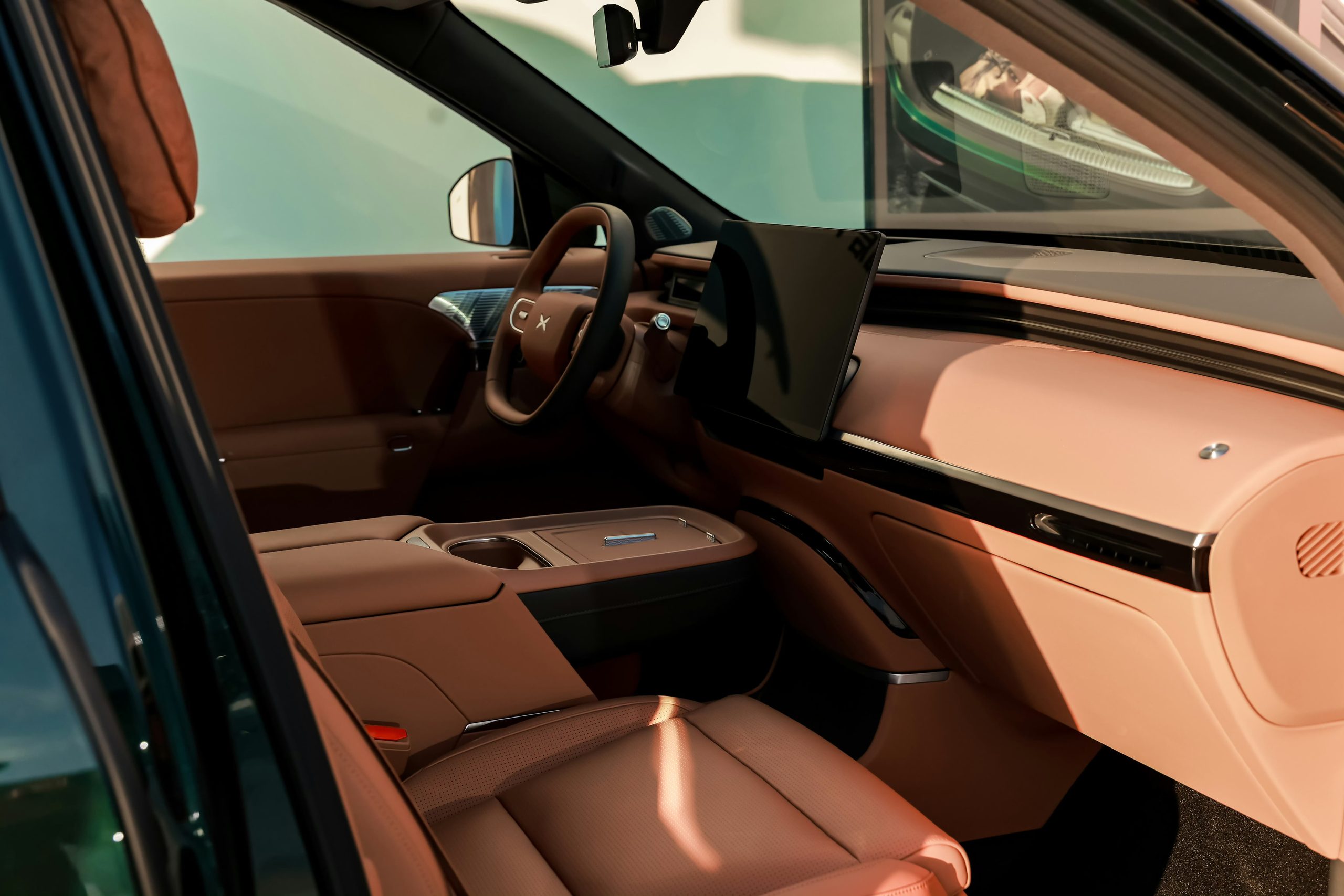 XPENG G9L front cabin in brown leather seen through the open driver door - steering wheel, screen and centre console