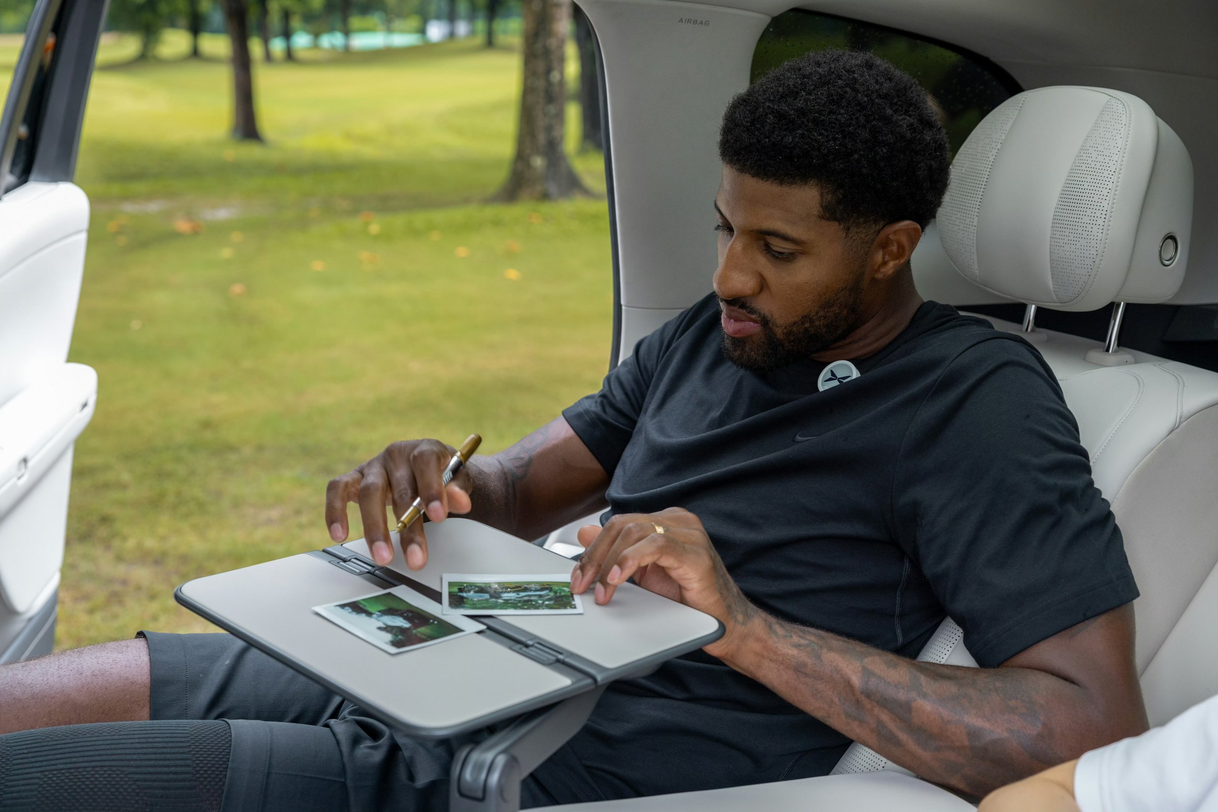 XPENG G9L hvidt bagsæde med Paul George ved det nedklappelige bakkebord