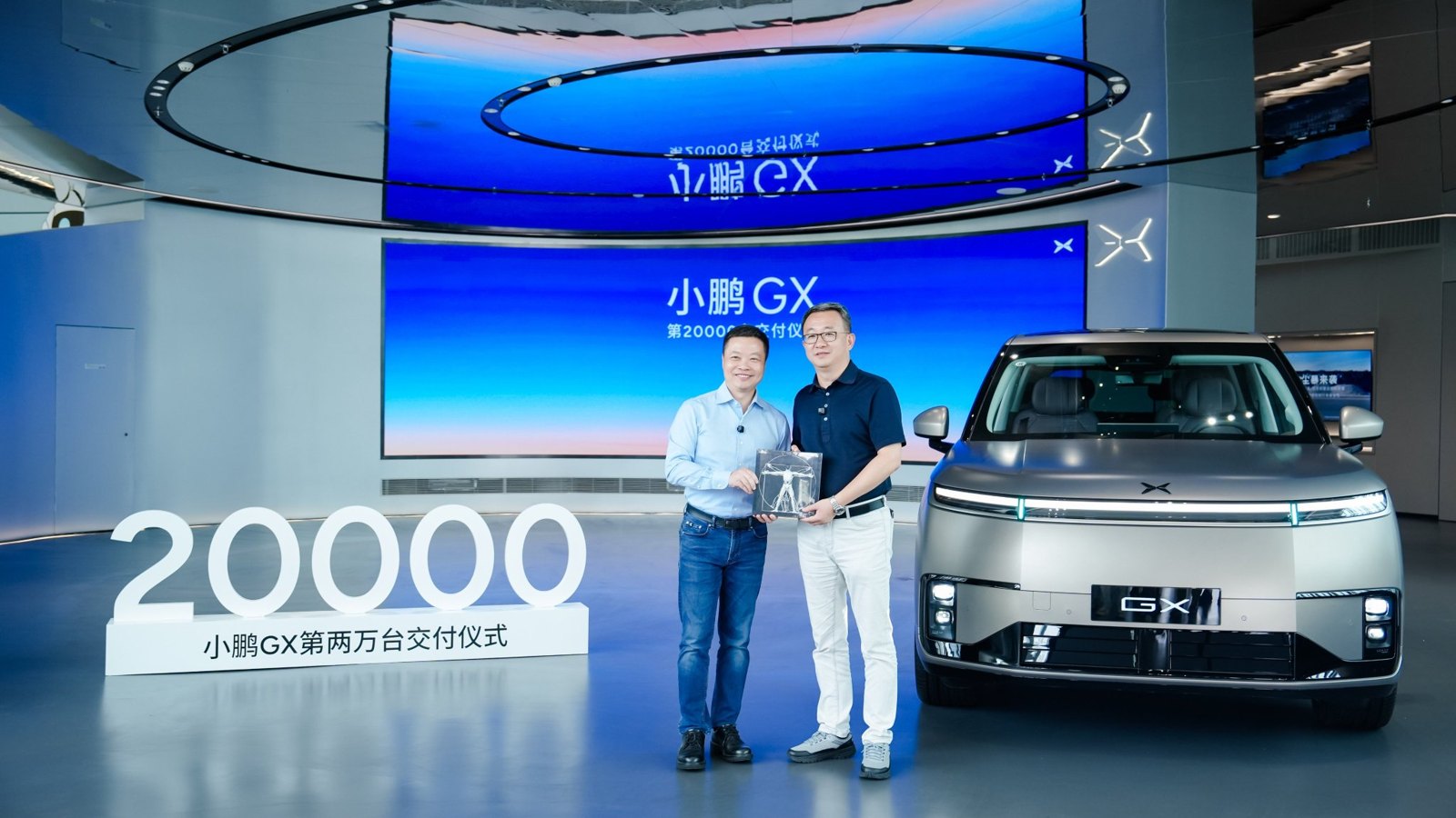 Overdragelse: He Xiaopeng og Bu Xinwen foran en hvid XPENG GX under et 20000-skilt