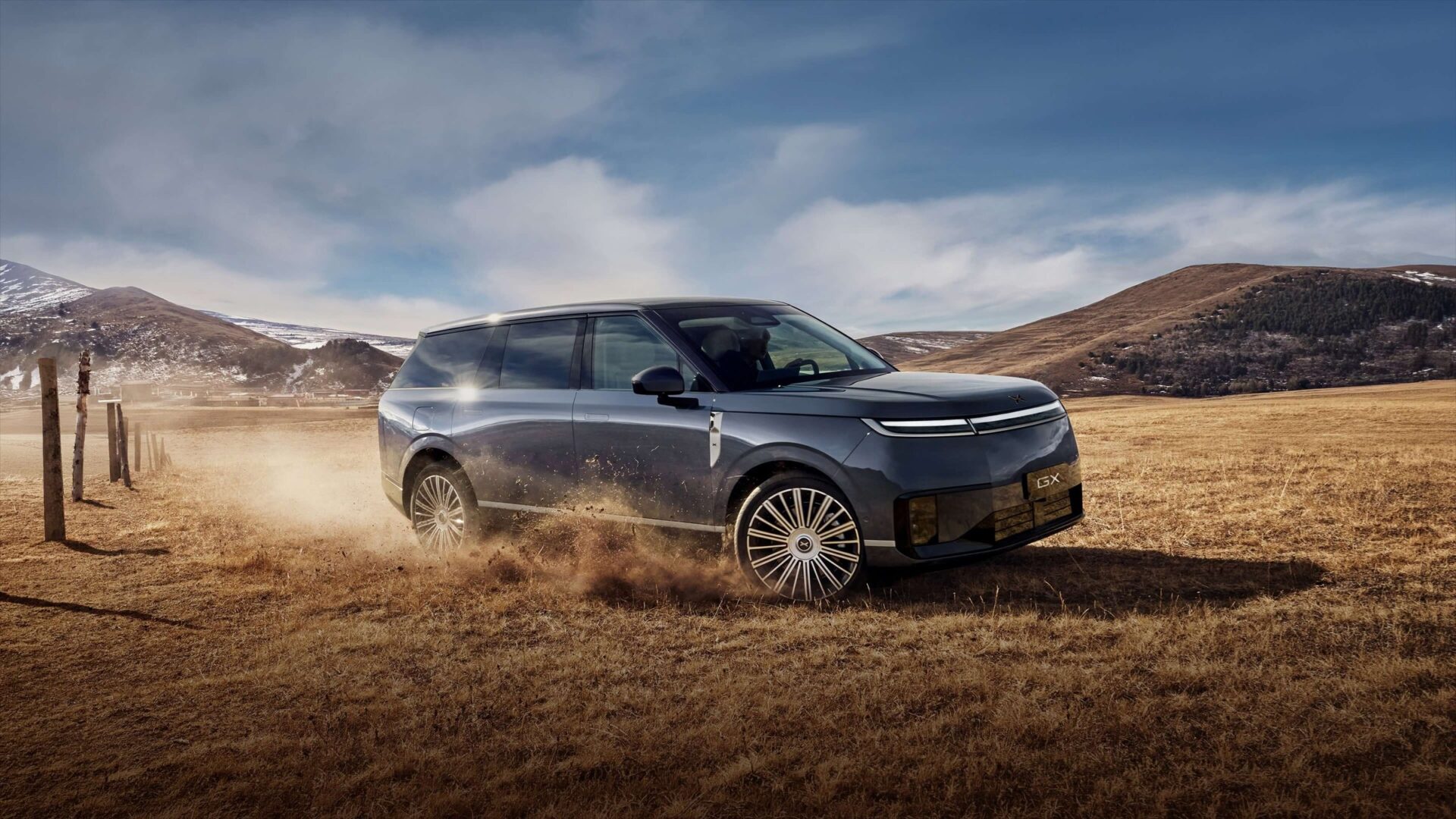 XPENG GX driving across dry grassland kicking up dust