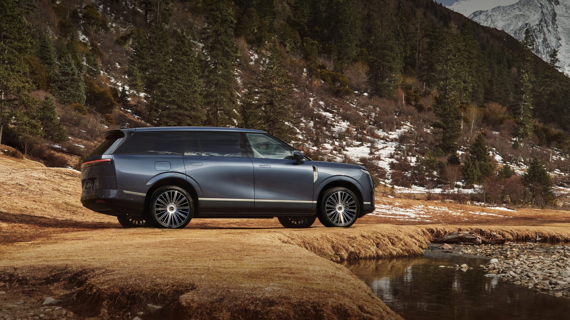 XPENG GX side profile by a mountain stream and forest