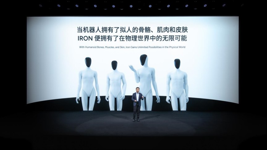 He Xiaopeng on stage in front of a screen showing four white IRON figures with different body shapes and the line With Humanoid Bones, Muscles, and Skin, Iron Gains Unlimited Possibilities in the Physical World