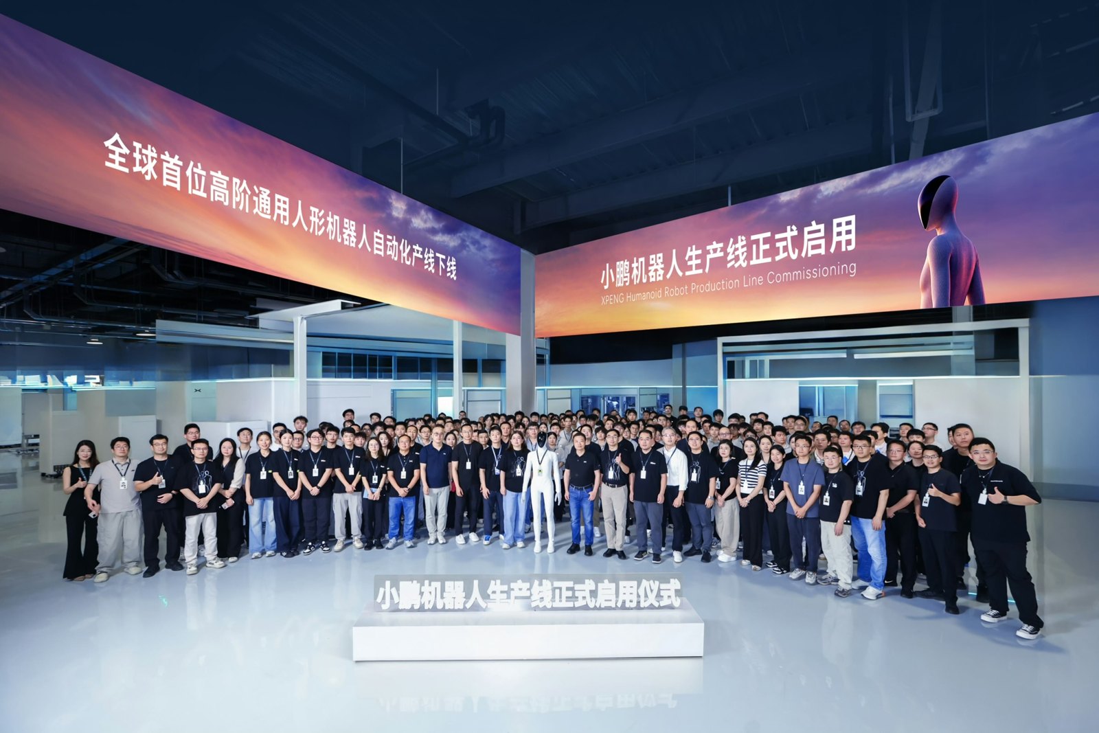 Group photo of XPENG's robotics team with an IRON robot in the middle, under banners marking the opening of XPENG's robot production line