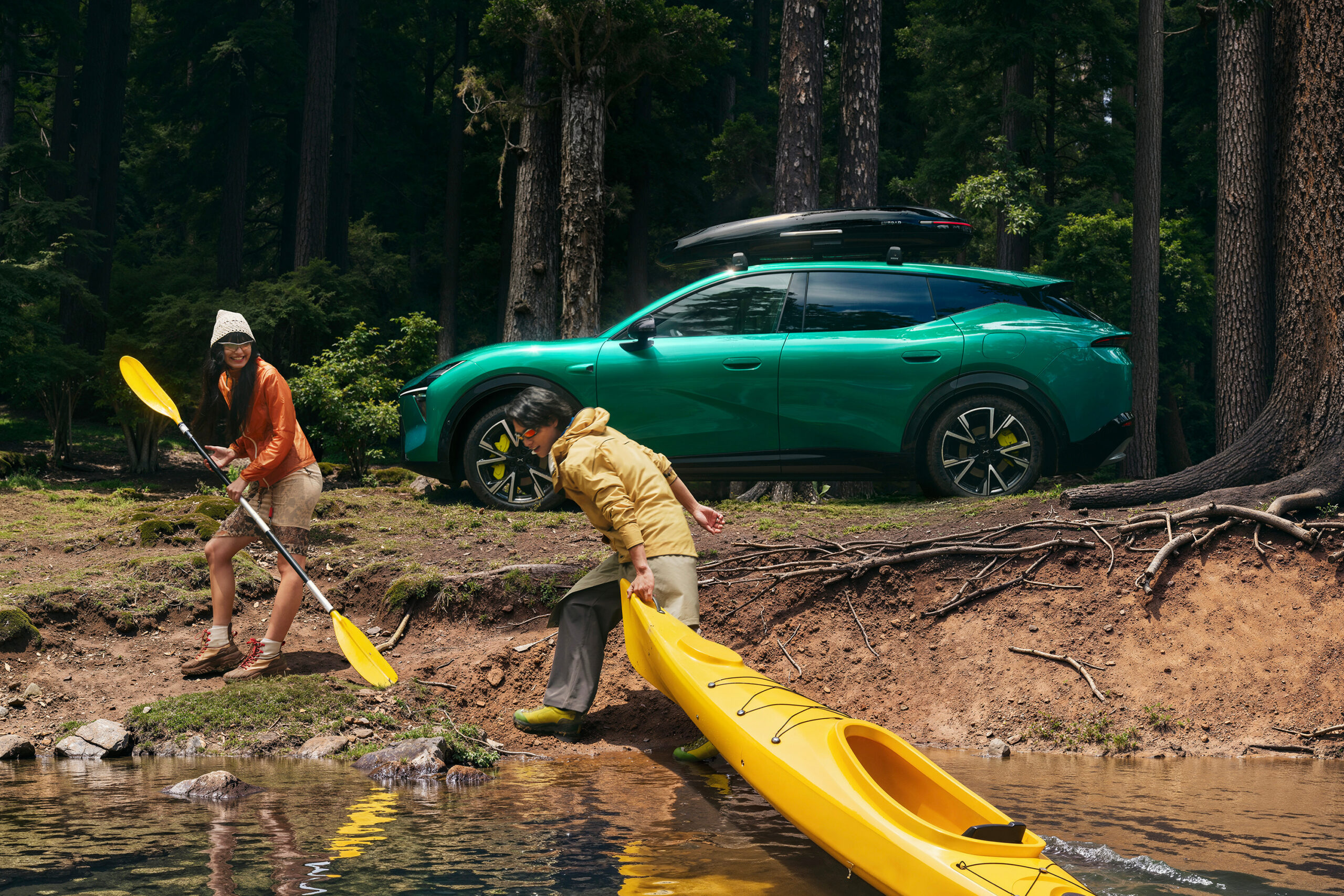 Green L05 with a roof box beside a kayak in a forest