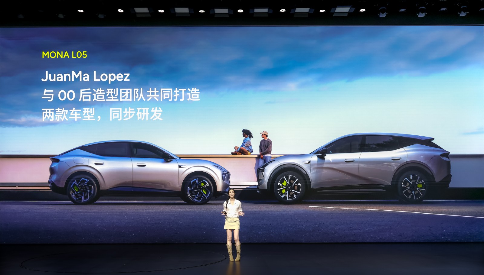 A presenter on stage in front of a slide showing the L03 and L05 side by side and a line about JuanMa Lopez and the design team