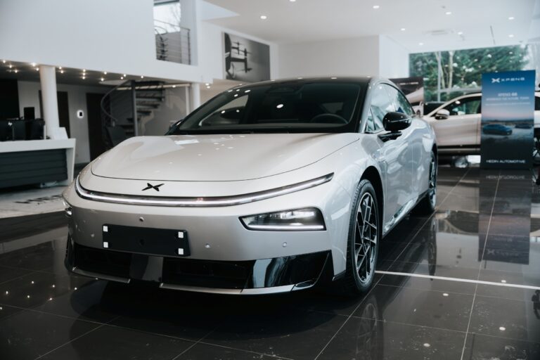 Silver XPENG P7+ in a German dealer showroom with a G6 and an XPENG banner behind it