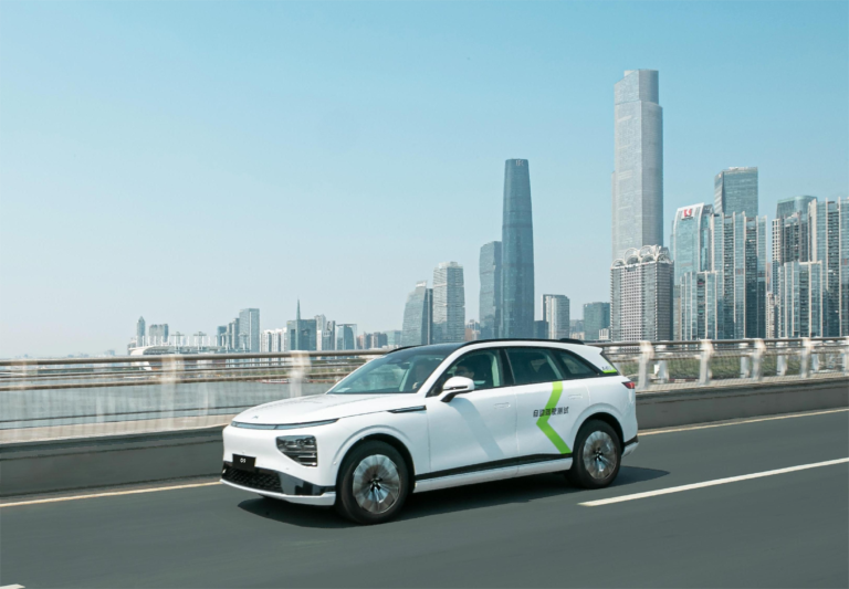 White XPENG G9 test car on an elevated road with the Guangzhou skyline behind