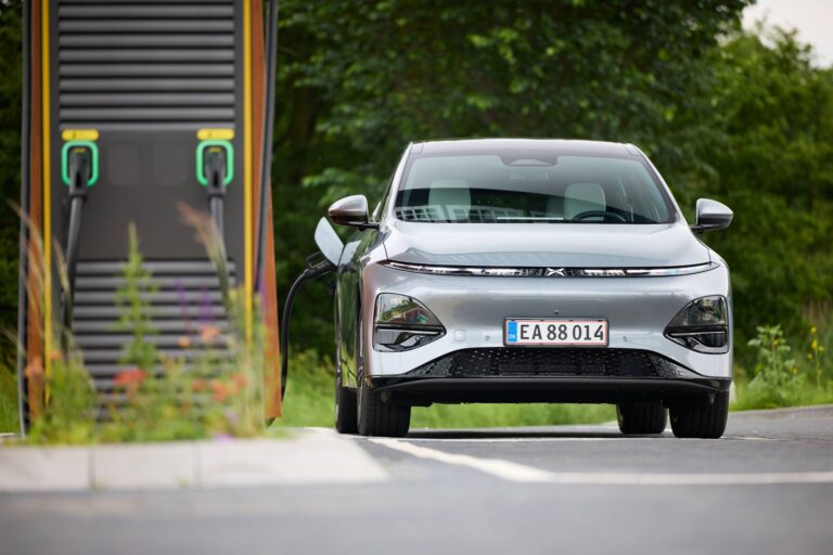 Silver XPENG G6 on Danish plates plugged into a DC charger on a rural road