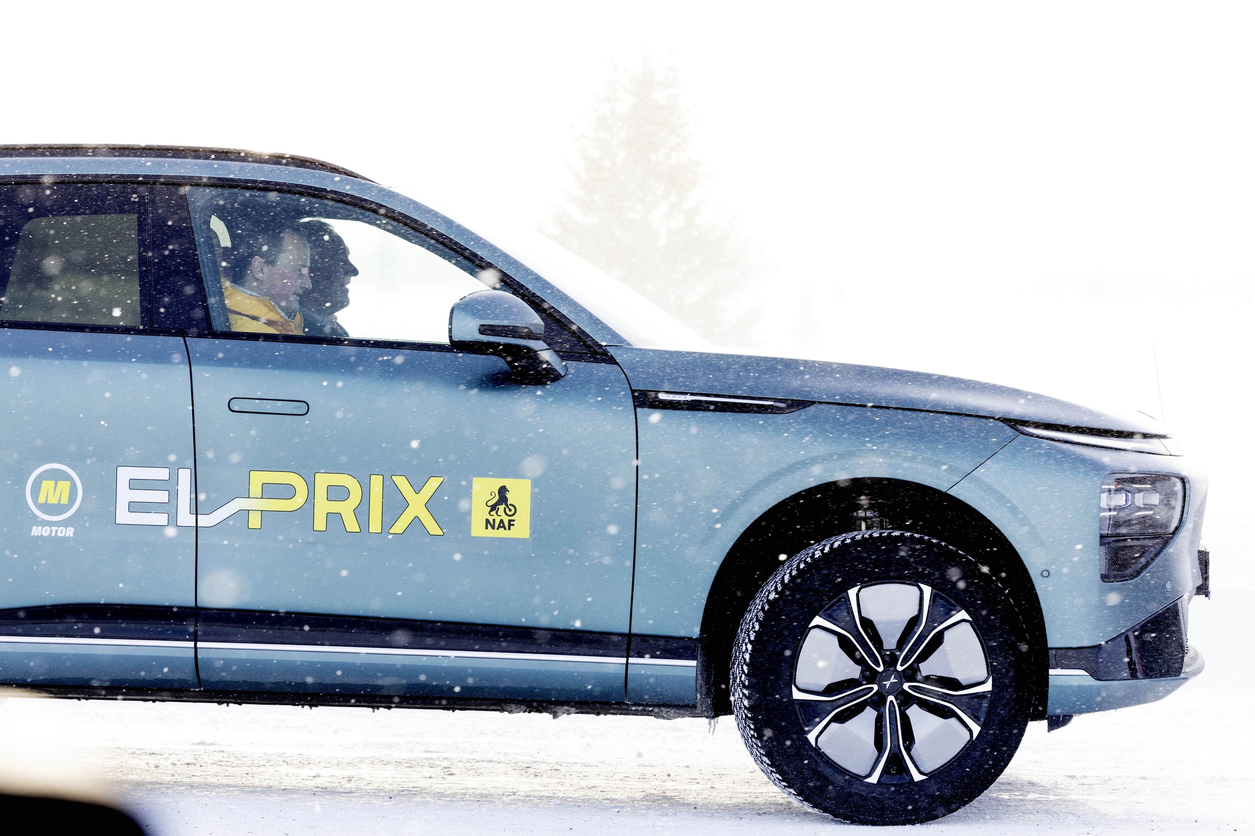 Blue green XPENG G9 in El Prix test livery driving through falling snow