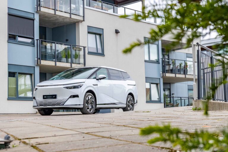 White XPENG X9 parked outside a Nordic apartment block
