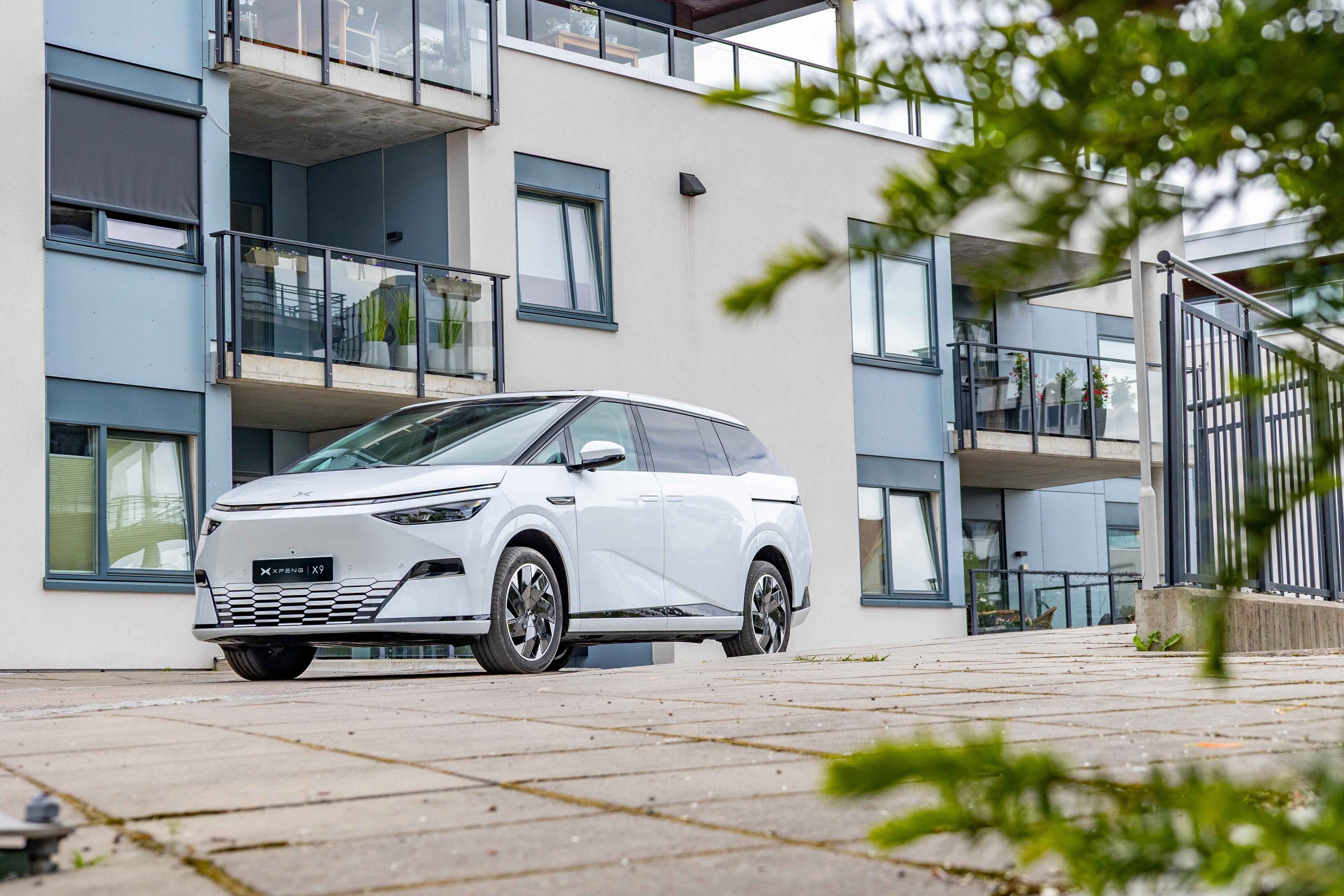 Hvid XPENG X9 parkeret foran en nordisk boligblok