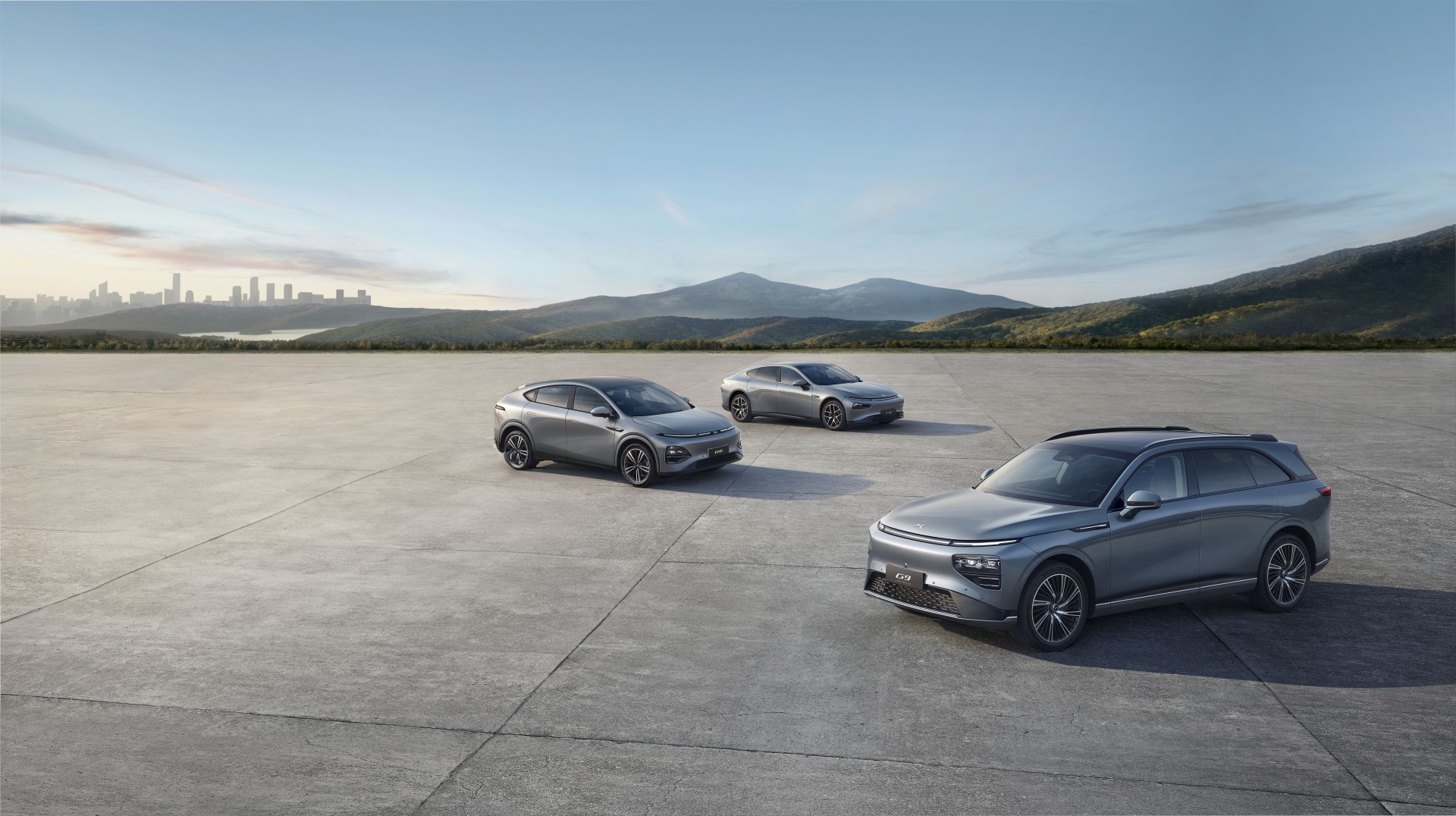 Grey XPENG G6, P7 and G9 on a concrete apron with hills behind