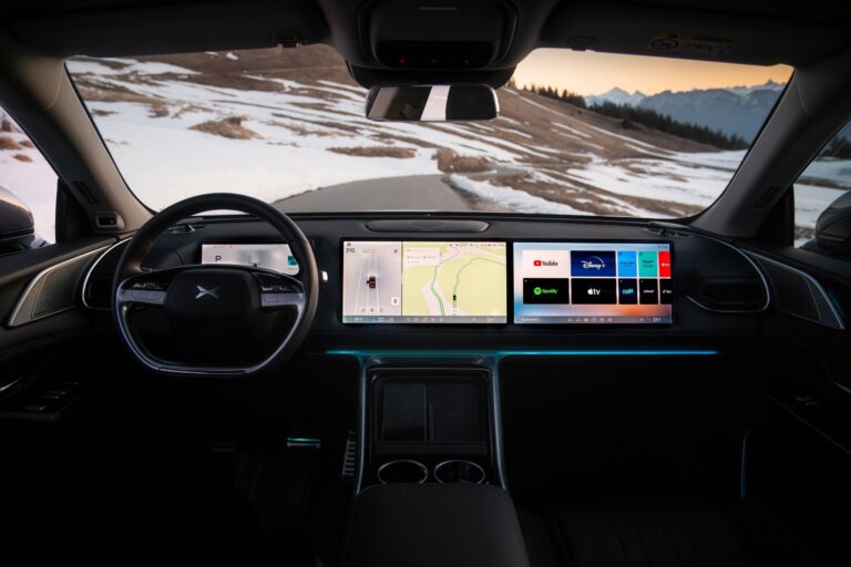 XPENG X9 cabin from the driver's seat on a snowy mountain road, three screens lit with a French interface