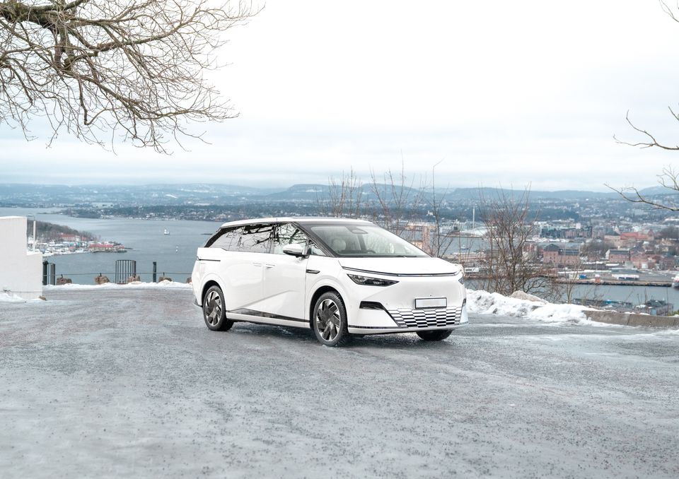 White XPENG X9 on a snow-dusted viewpoint above the Oslo fjord in winter