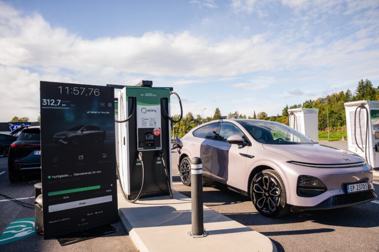 Stellar Purple XPENG G6 on Norwegian plates at an Eviny 50 to 500 kW charger with a display showing a stopwatch at 11 minutes 57 seconds