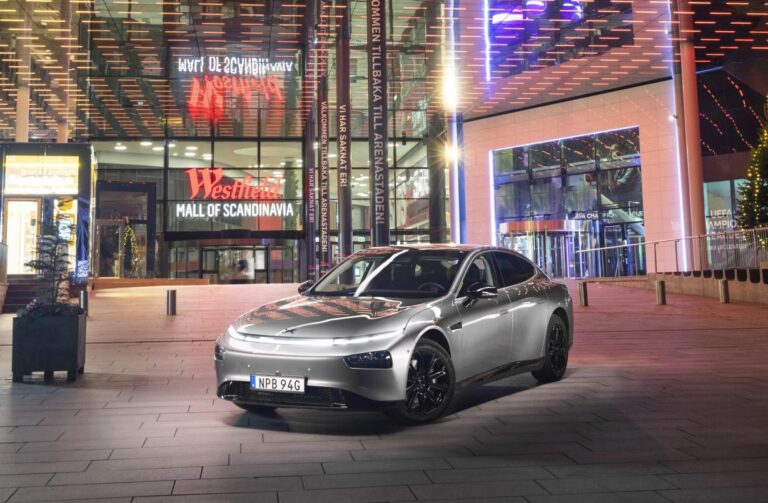Silver XPENG P7 parked at night outside the lit entrance of Westfield Mall of Scandinavia in Stockholm