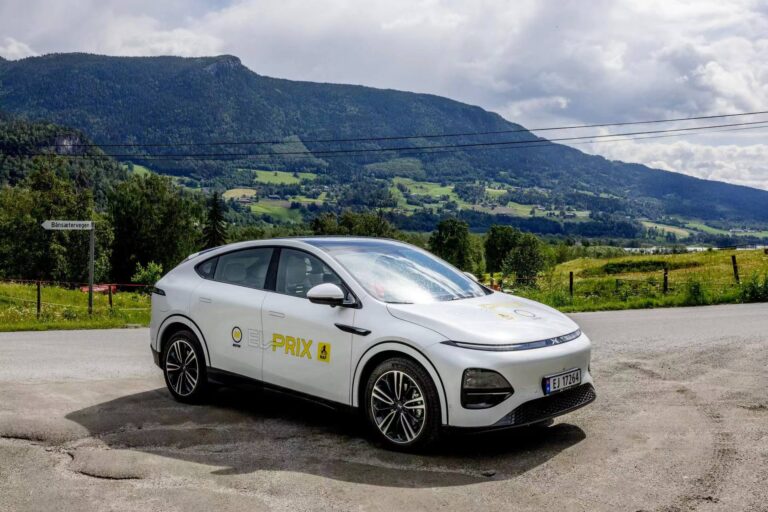 White XPENG G6 with EL-PRIX decals parked on a gravel verge in a green Norwegian valley