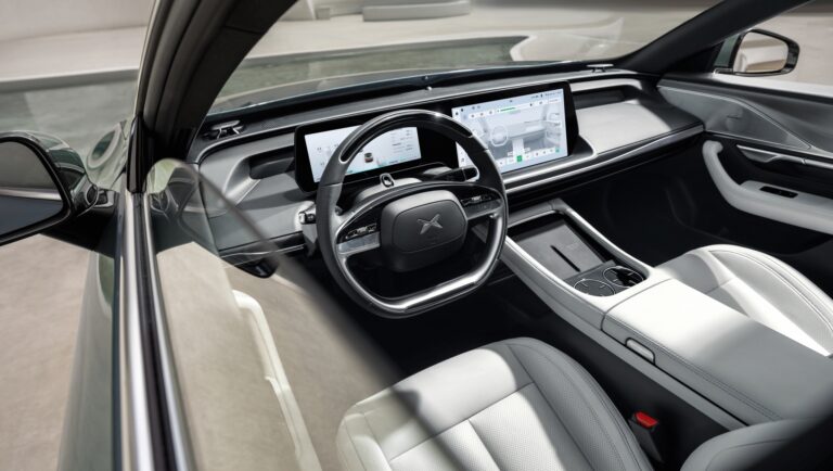 XPENG P7 cabin seen through the open driver's door, pale quilted leather seats and twin dashboard screens
