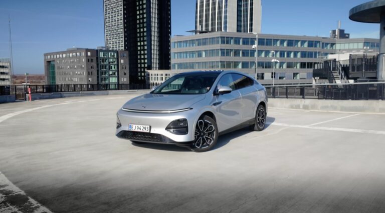 Silver XPENG G6 on an open rooftop car park with a modern office skyline behind it