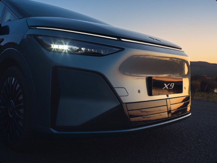 XPENG X9 front detail - full-width LED light bar with the XPENG mark on the bonnet above it