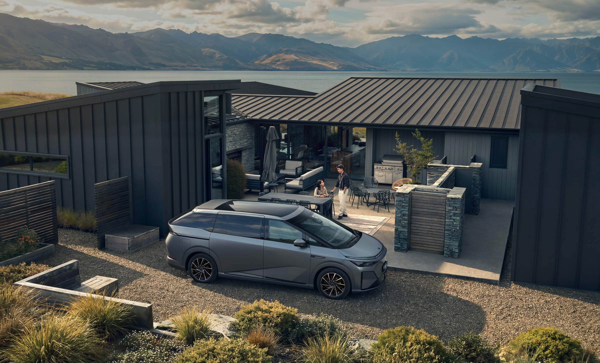 XPENG X9 in Silver Frost parked on a gravel drive at a lakeside house